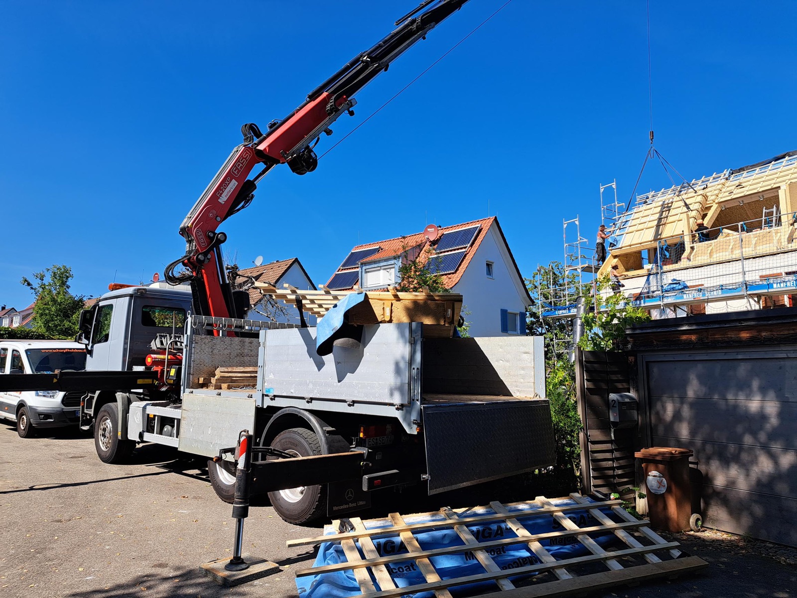 Ladekran hebt ein vorgefertigtes Dachelement über das Haus